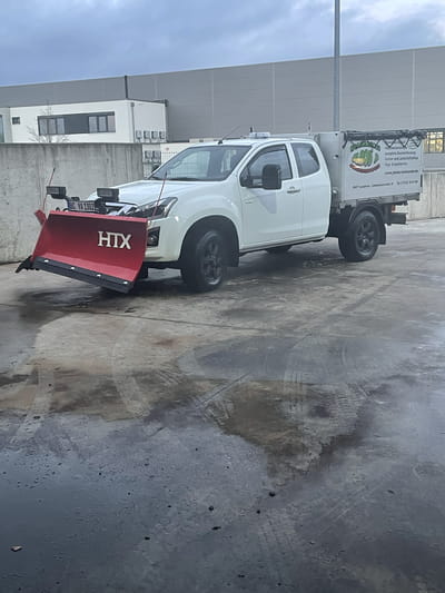 Pickup mit HTX-Schneepflug und Streugutaufbau auf dem Betriebshof